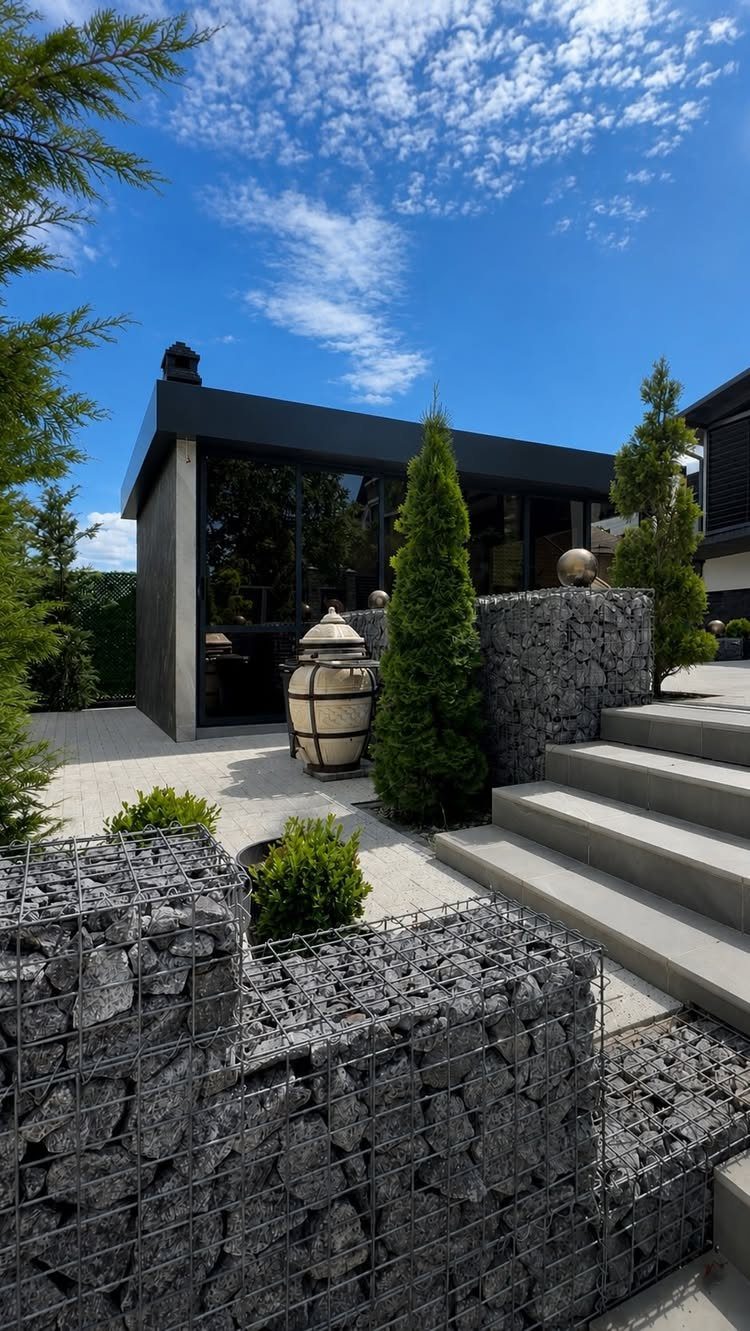 20 Backyard Gardening Inspiration Ideas for Every Outdoor Space 14 Grey stone gabion walls and concrete steps in a modern landscaped backyard patio area.