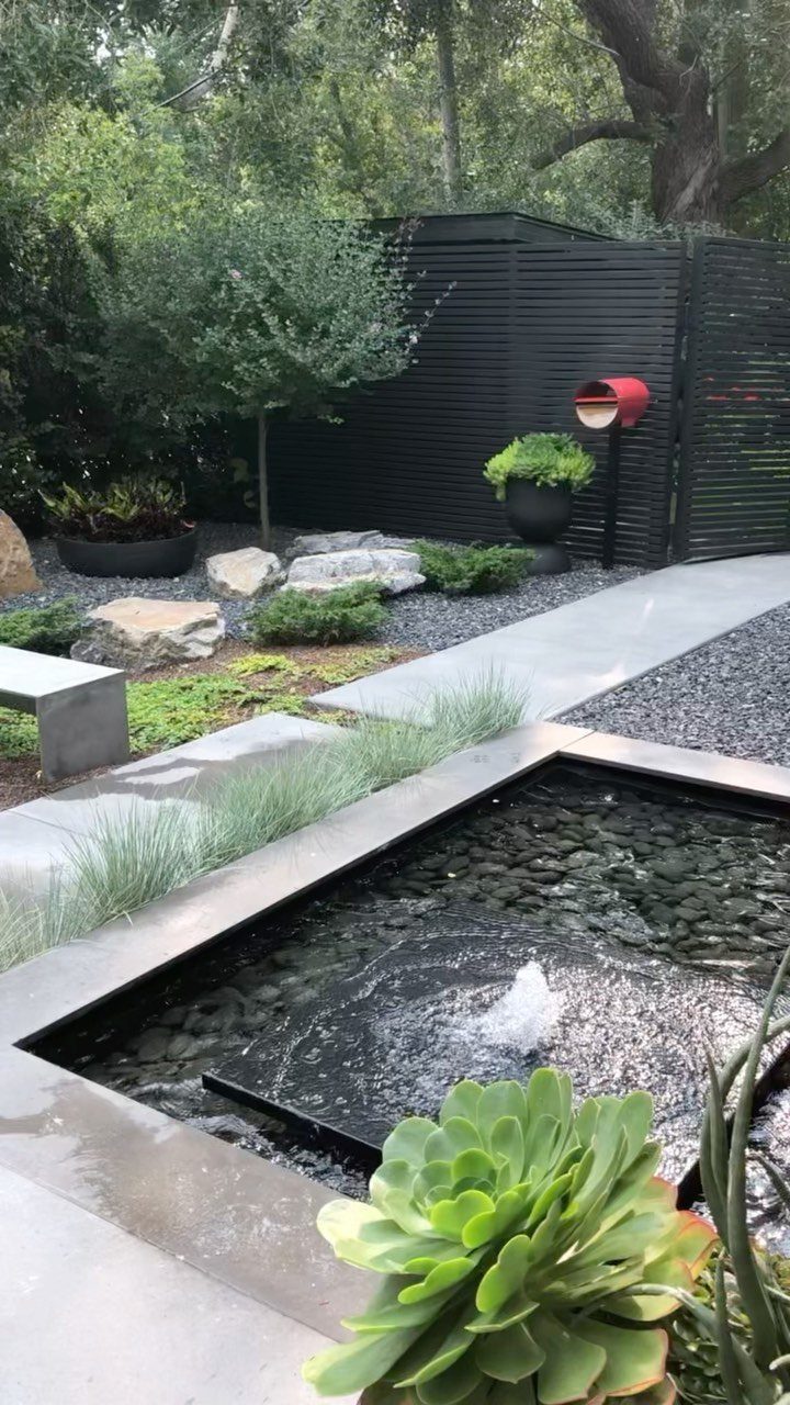 20 Backyard Gardening Inspiration Ideas for Every Outdoor Space 20 A modern rectangular water fountain bubbling amidst dark stones and green succulent plants.