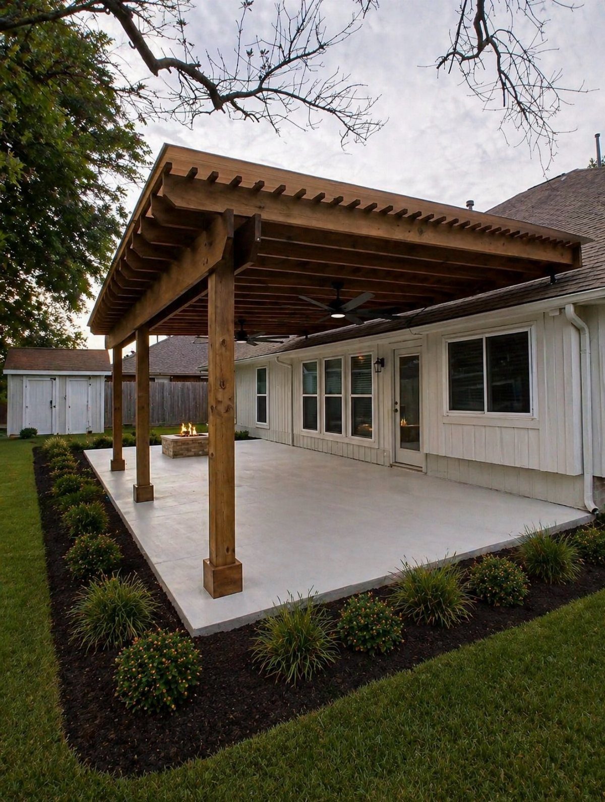 21 Backyard Landscape Design Ideas for Outdoor Living 10 A large wooden pergola structure covering a concrete patio next to a white house.