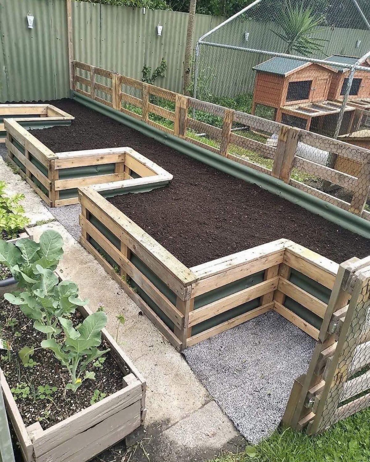 Wooden raised garden beds arranged in a zigzag geometric pattern filled with dark soil outdoors.