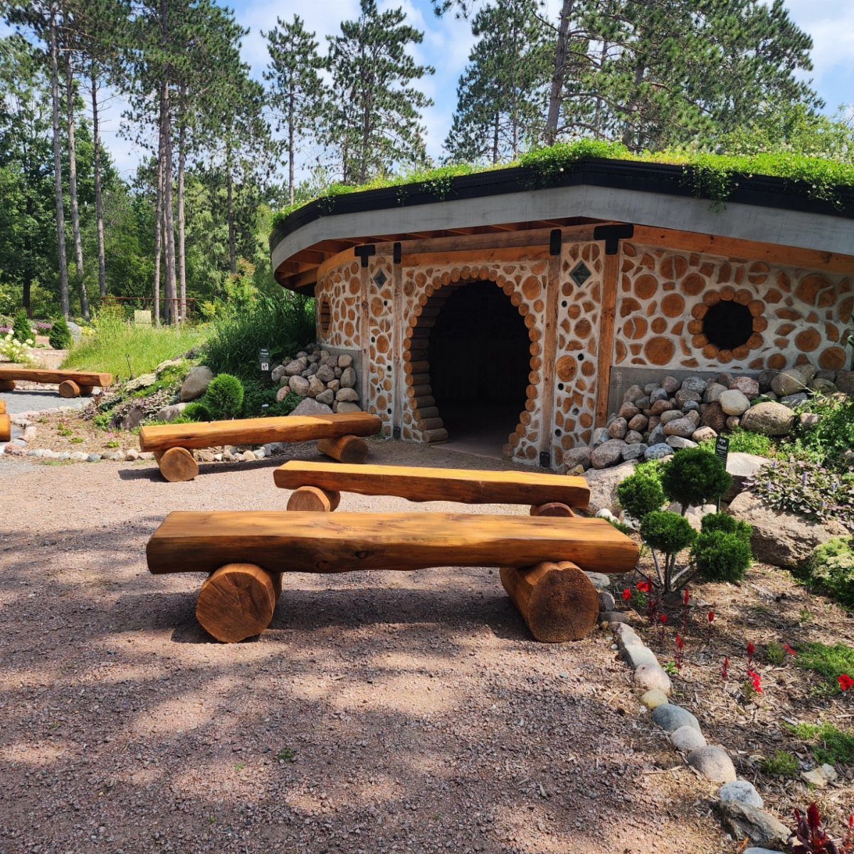 DIY Garden Bench: 8 Plans from Classic Backrests to Cinder Block Builds 5 Three rustic log benches sit on a gravel path in front of a stone building.