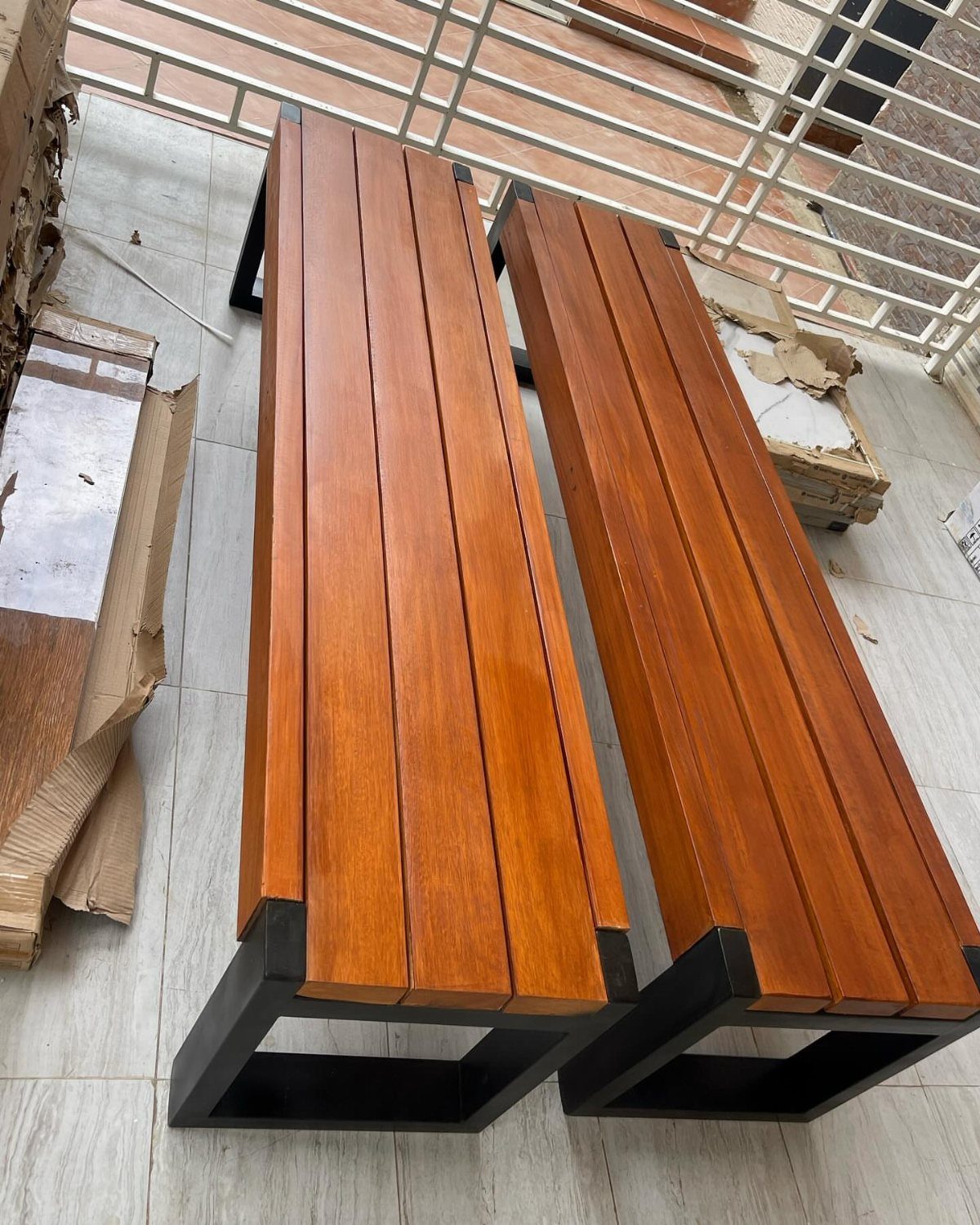 DIY Garden Bench: 8 Plans from Classic Backrests to Cinder Block Builds 6 Two modern wooden slat benches with black metal frames resting on a tiled floor.