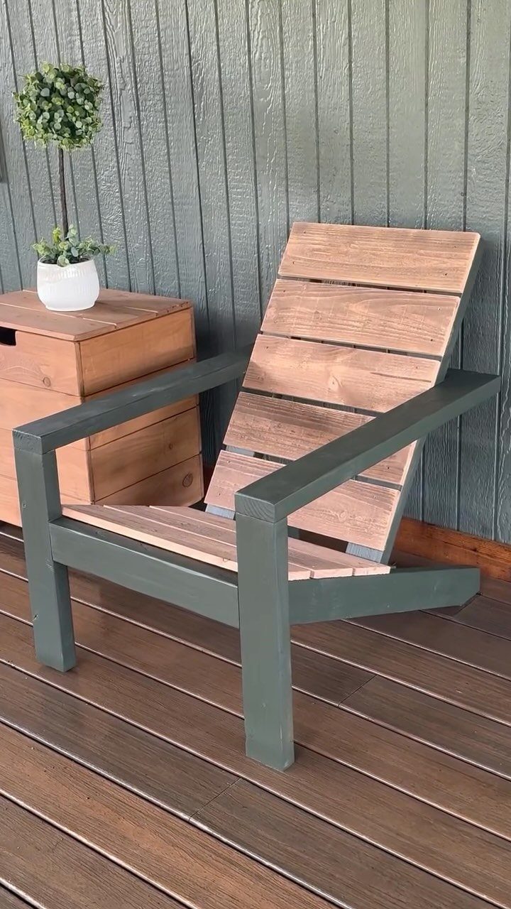 9 DIY Outdoor Furniture Ideas: Pallet Tables to Adirondack Chairs 1 A modern Adirondack chair with a dark green frame and natural wood slats on a deck.
