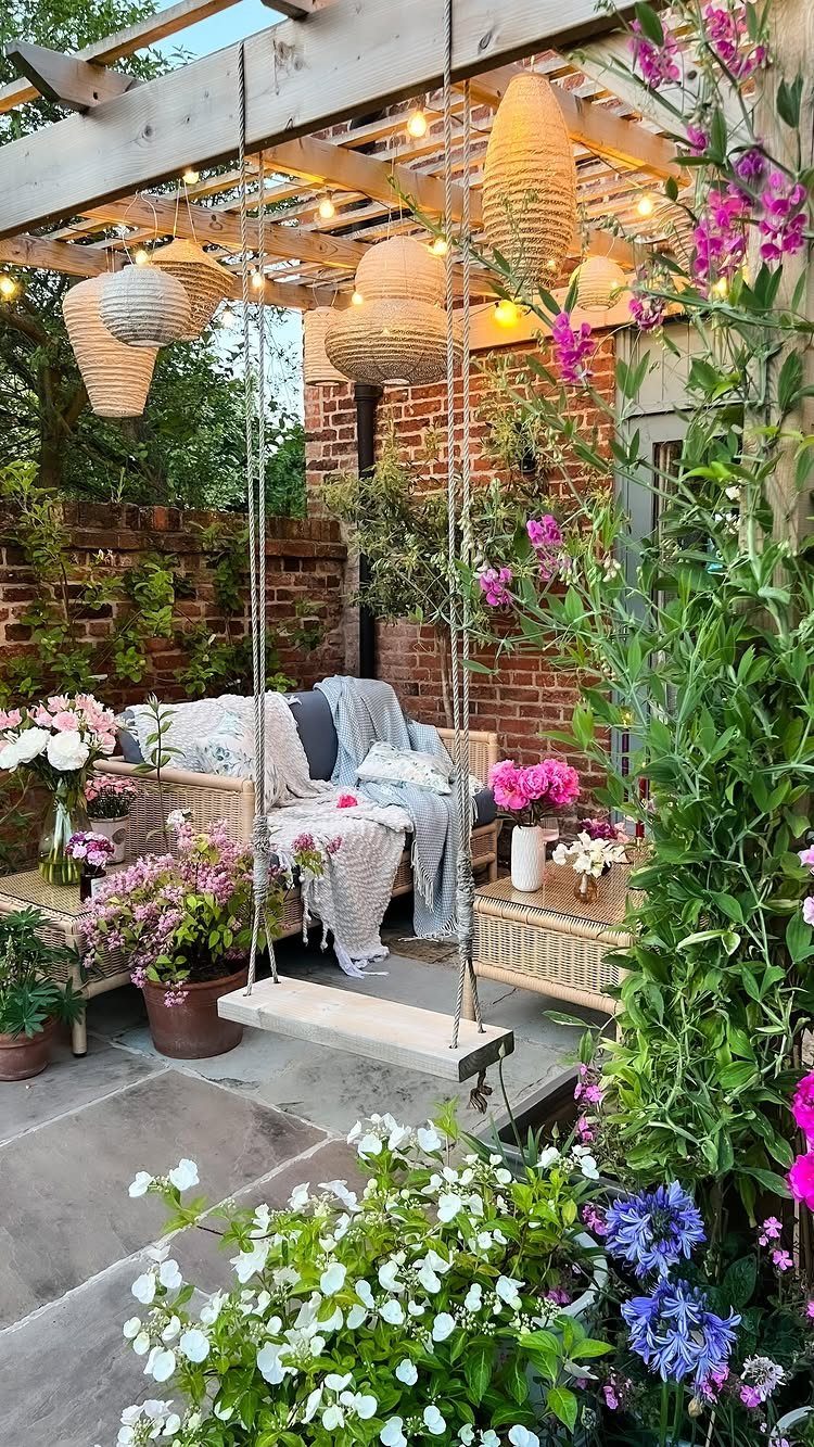 12 Dream Backyard Garden Ideas with Outdoor Kitchens to Natural Pools 3 A wooden pergola decorated with woven hanging lamps and string lights over a flowering patio garden.