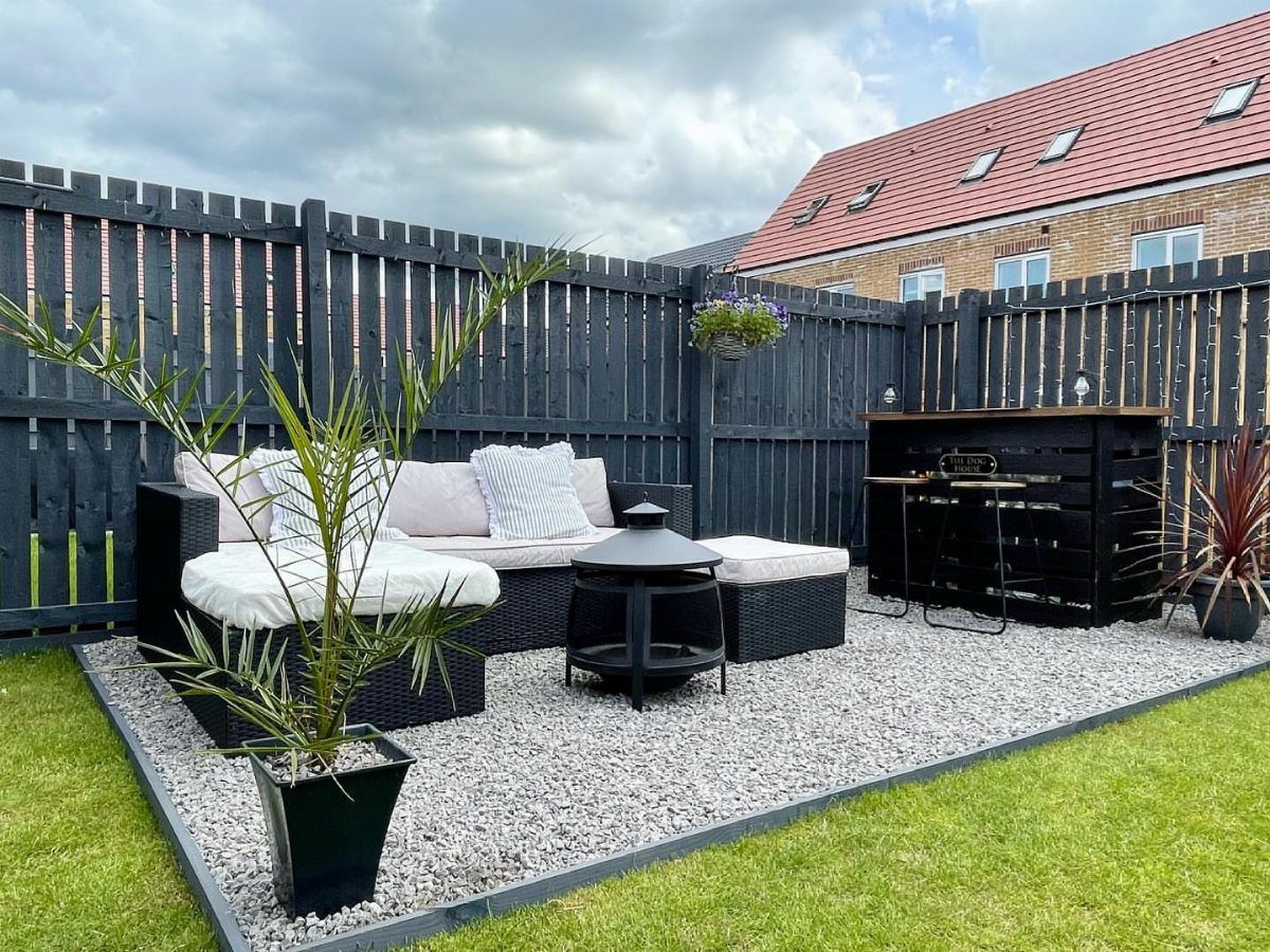 7 Easy DIY Patio Ideas With Paver Floors, Pallets and Gravel 4 Black wicker outdoor furniture set on a light grey gravel patio surrounded by a black fence.