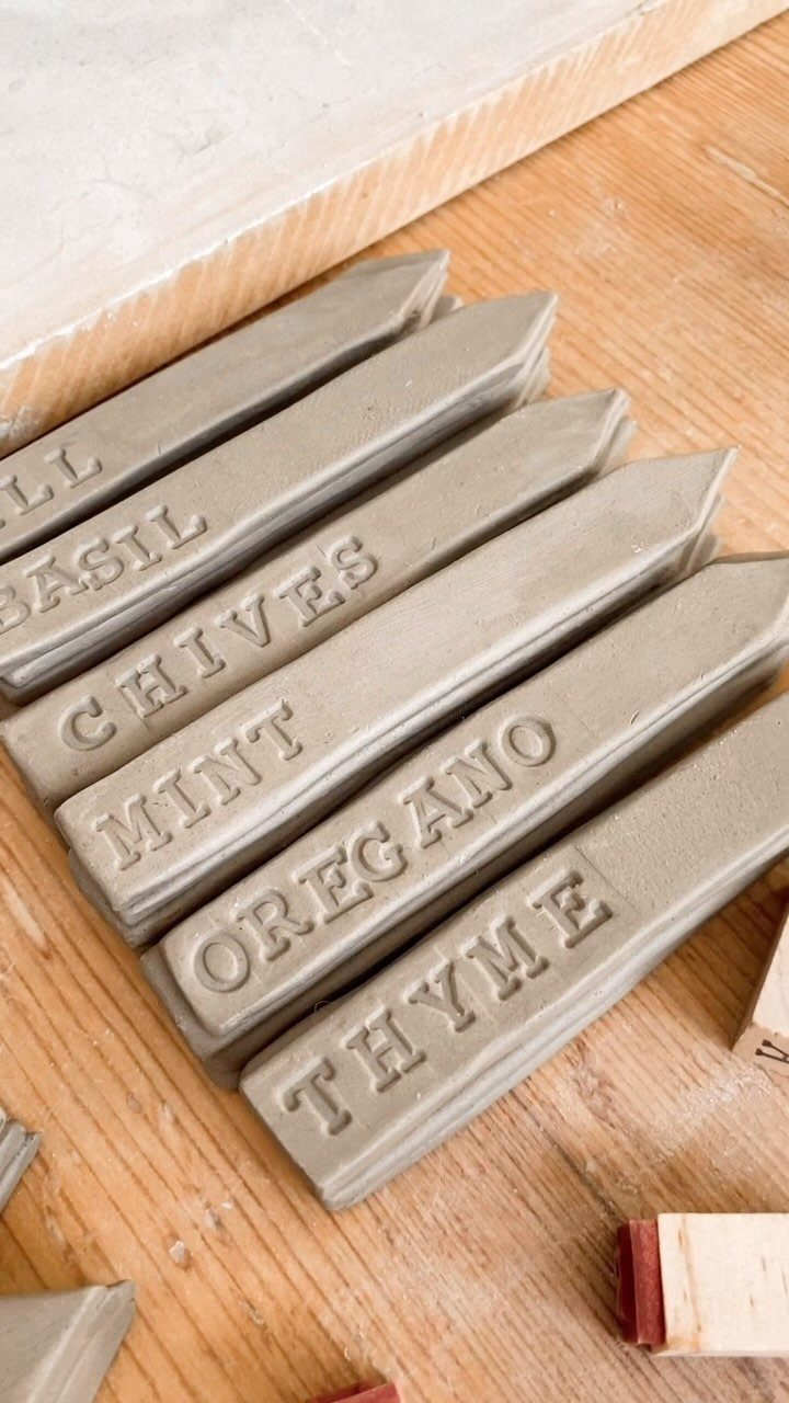 Garden Markers With Rocks: 3 DIY Ideas 3 Clay garden markers with embossed herb names like Mint and Oregano resting on a wooden table.