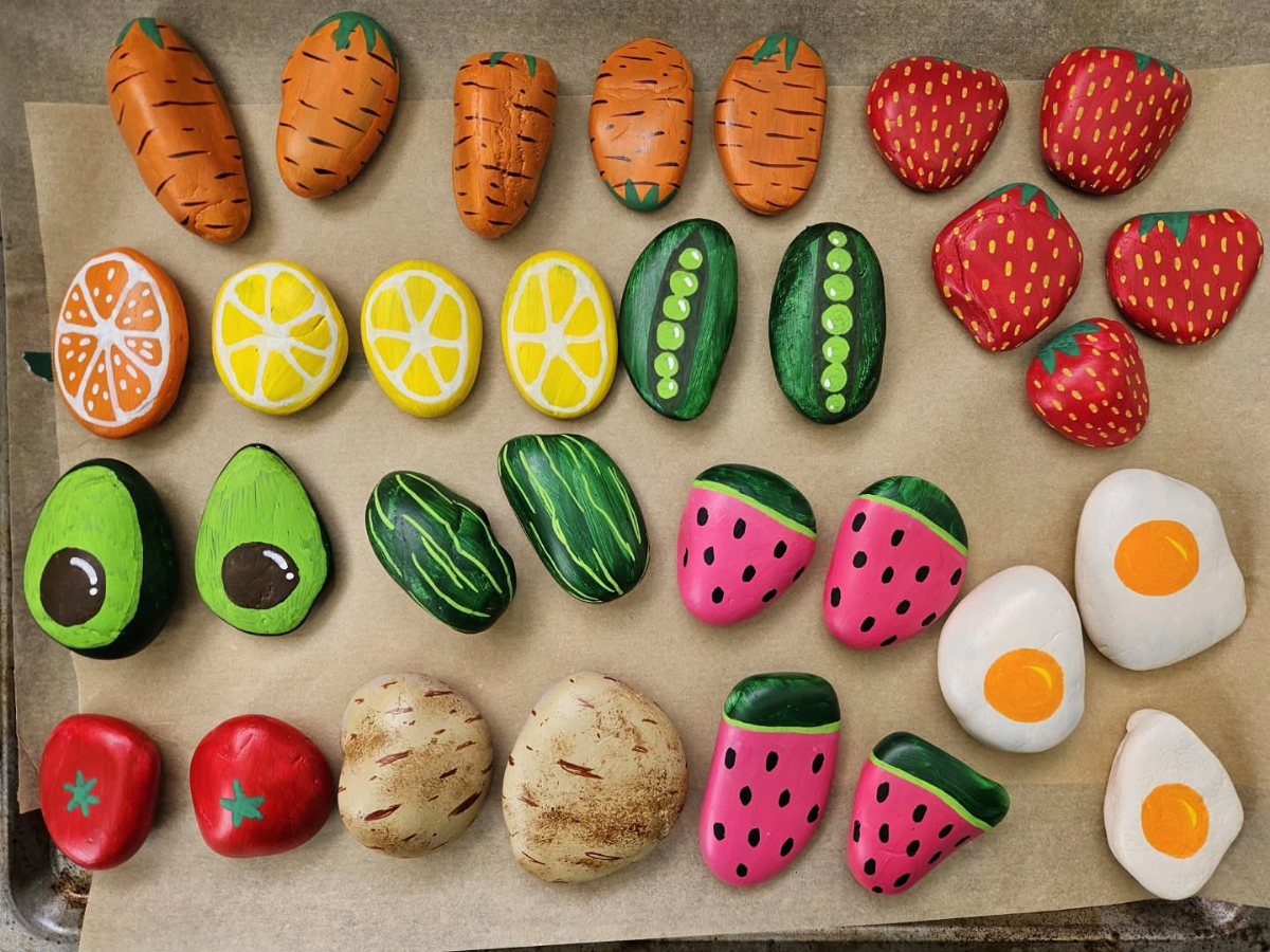 Garden Markers With Rocks: 3 DIY Ideas 1 Painted river rocks shaped and colored to resemble various fruits and vegetables on brown paper.