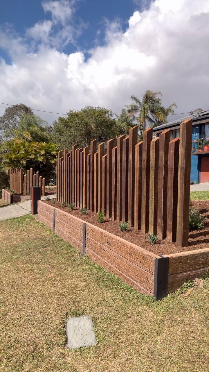 16 Lawn Border Ideas from Steel to Glass Bottle Edges 15 Wooden raised garden bed with vertical timber slats and small plants on a grassy lawn.