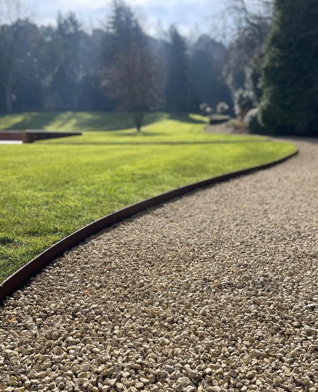 16 Lawn Border Ideas from Steel to Glass Bottle Edges 3 A thin metal edging strip separating a green lawn from a gravel pathway.