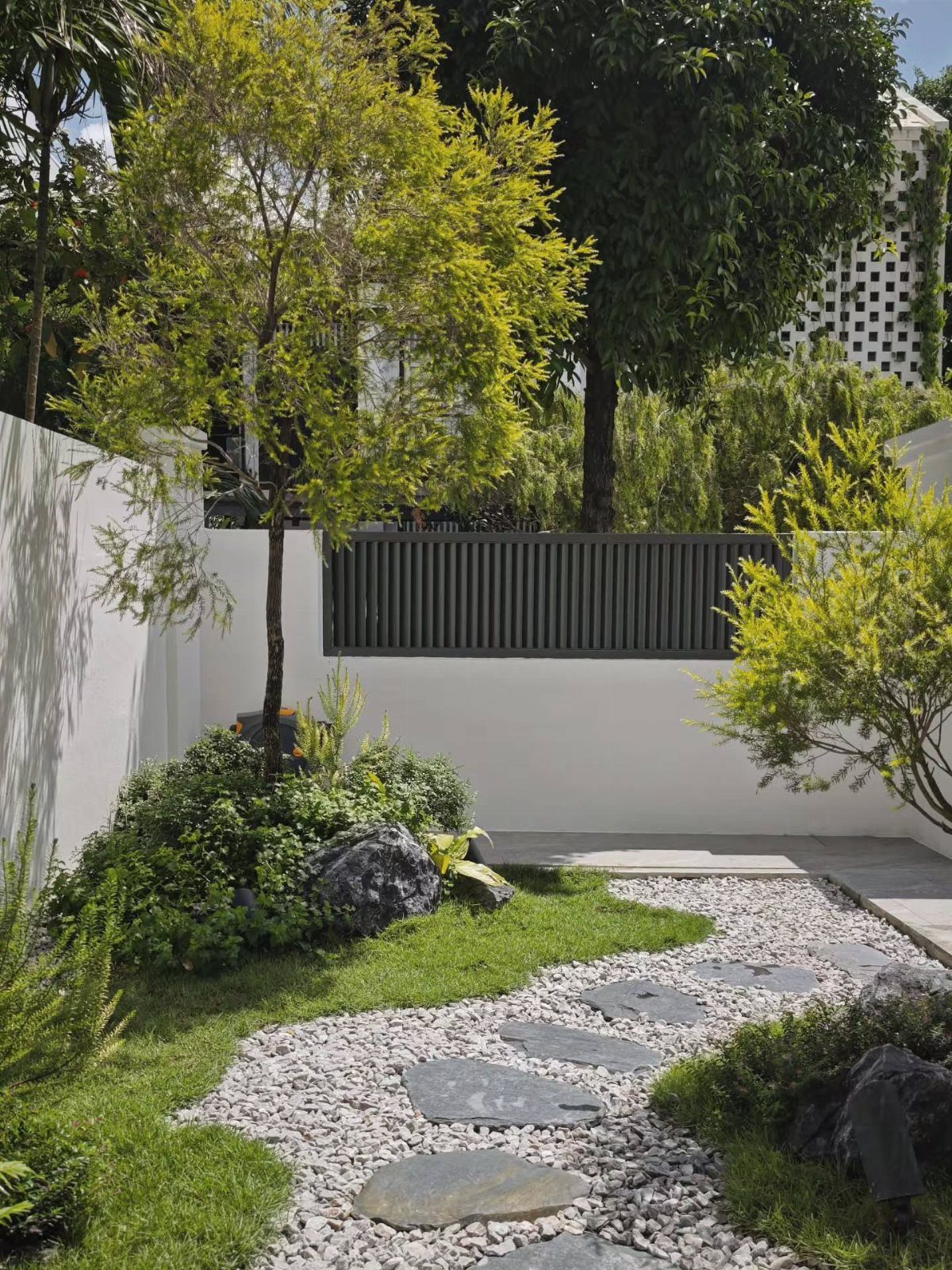 Stepping stones embedded in a white pebble path winding through a lush green garden.