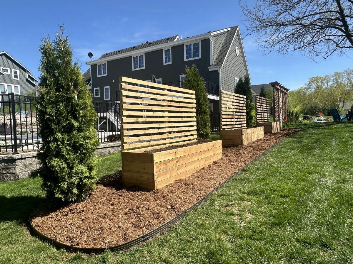 8 Raised Garden Bed Fence Ideas for Plants, Privacy, and Pests 1 Wooden raised garden beds with integrated horizontal slat trellises in a backyard garden setting.