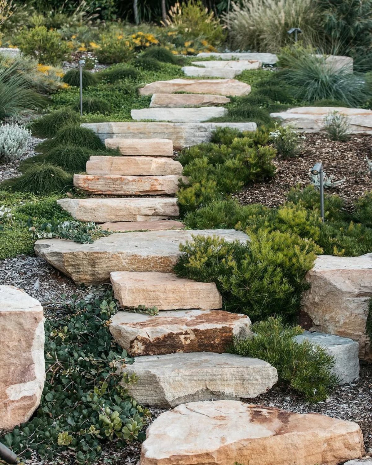 11 Rock Garden Ideas for Stone, Succulents and Alpine Plants 7 Flat natural stone slabs arranged as a winding path through a green garden landscape.