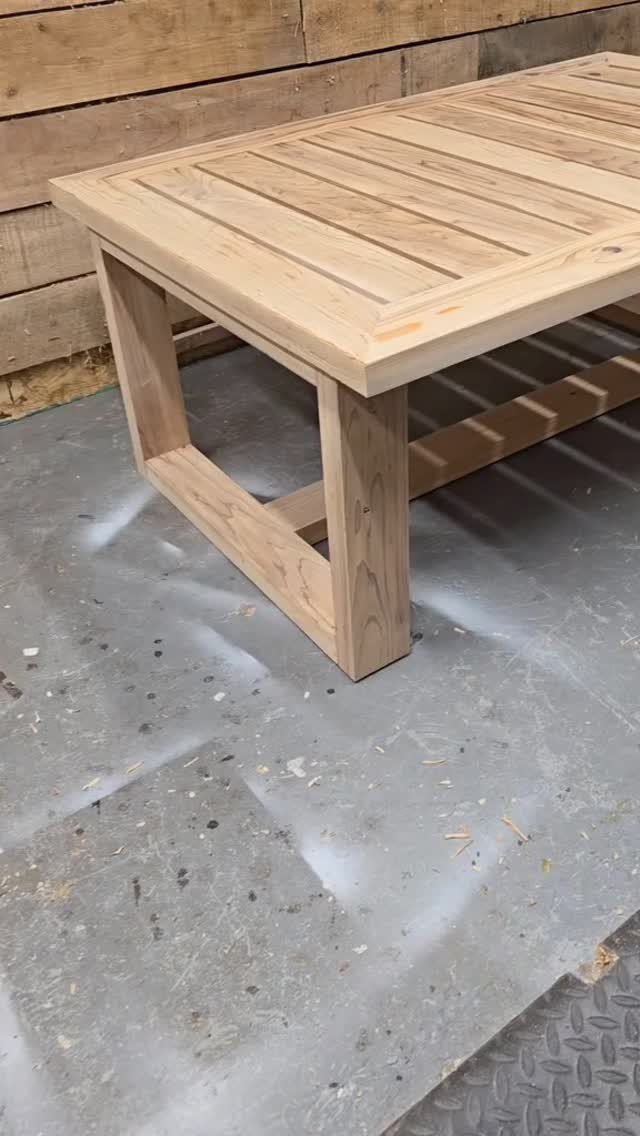 A light-colored wooden slatted coffee table sitting on a workshop floor.