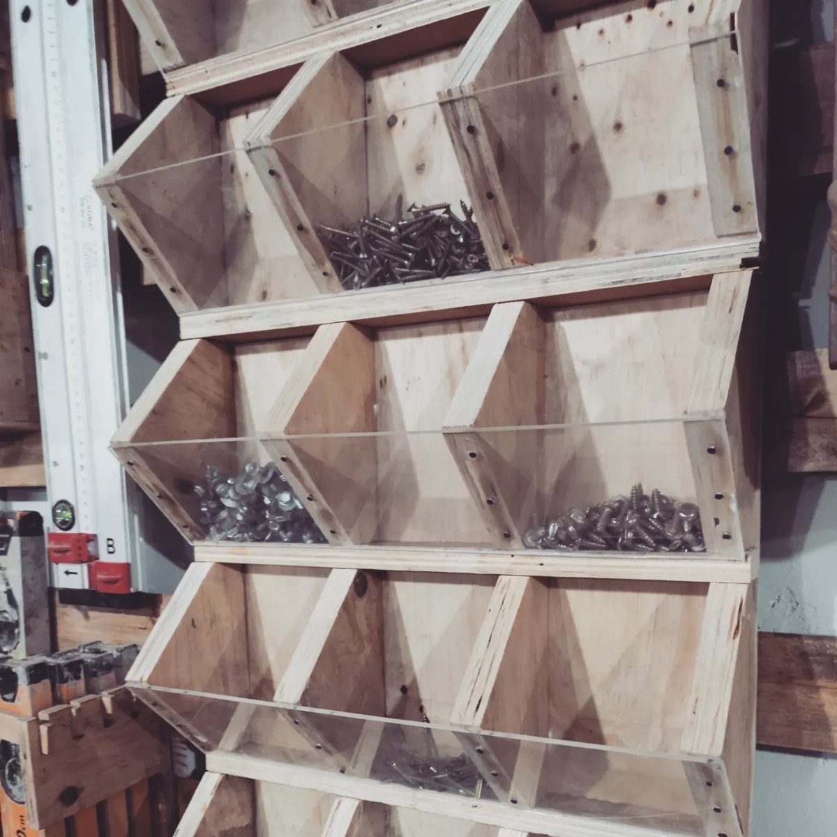 Wooden wall-mounted organizer bins filled with various metal screws and fasteners.