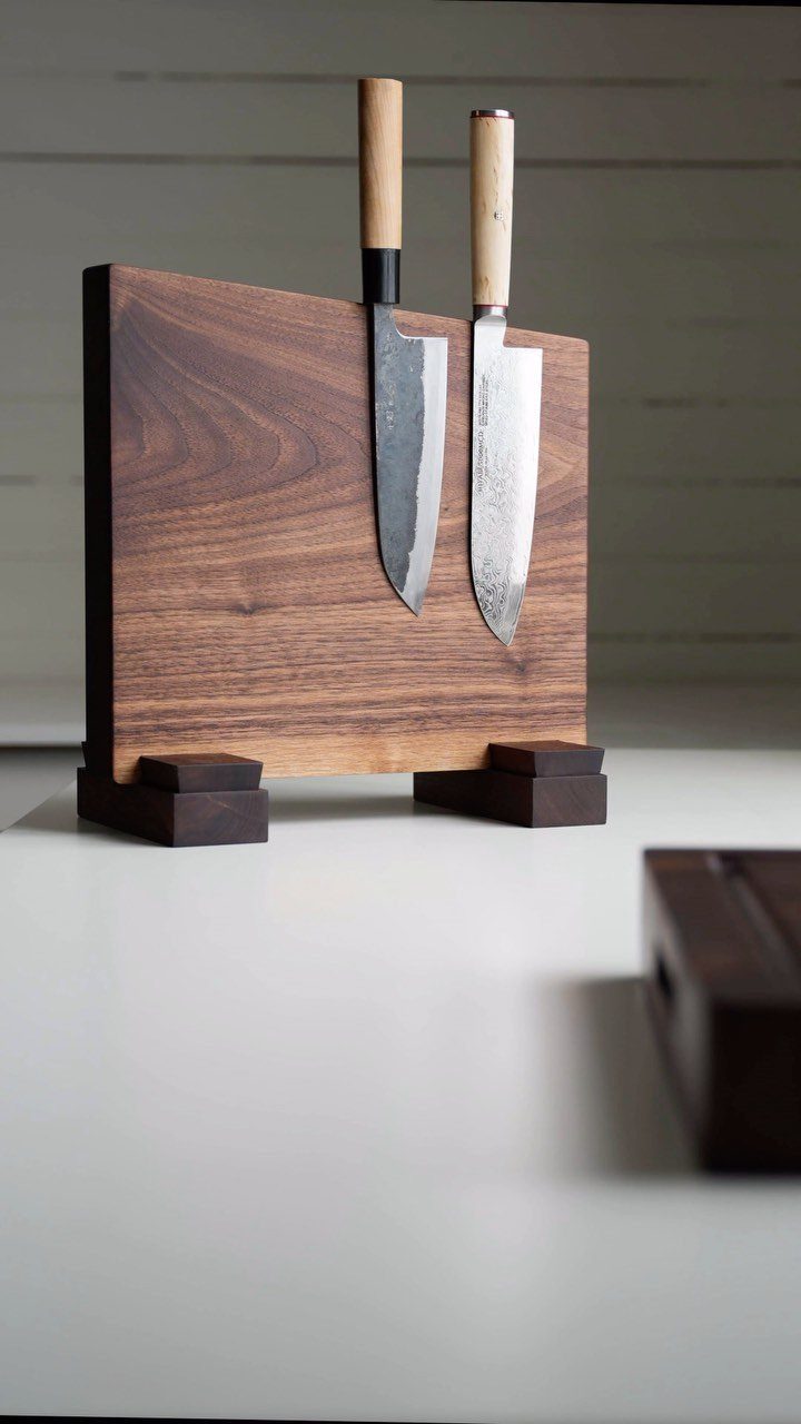 Two kitchen knives held upright in a thick rectangular dark wood knife block.